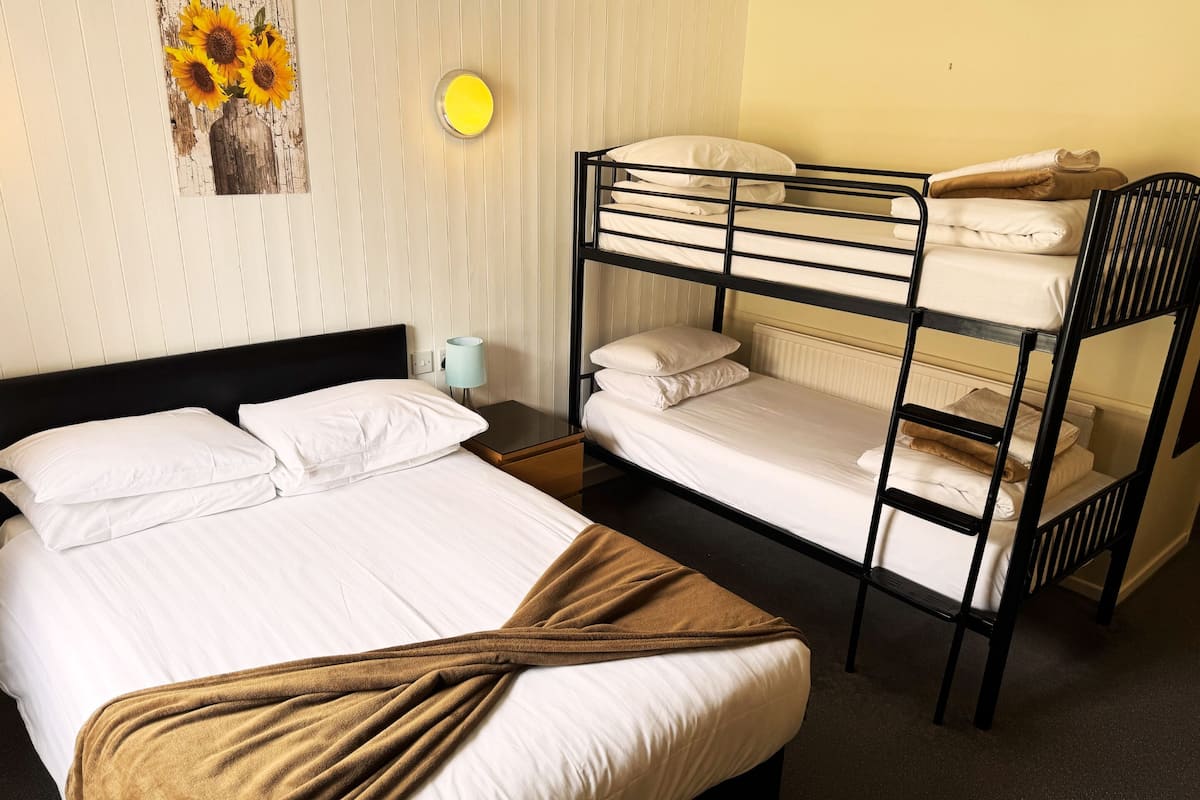 A bunk bed room with a single bed, a nightstand, a lamp, and a wall-mounted light fixture.