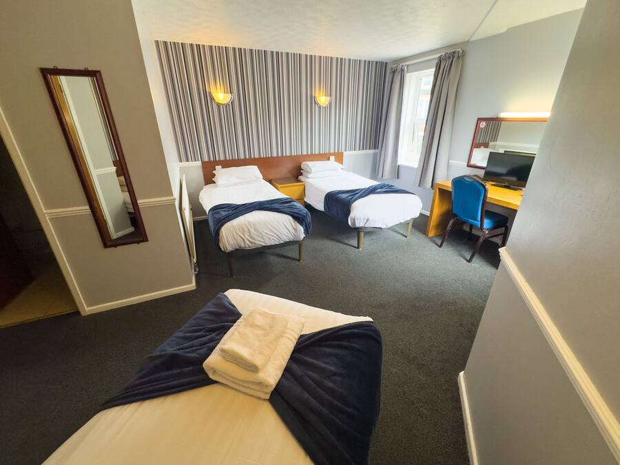 A hotel room with two beds, a desk, a chair, a TV, and a mirror.