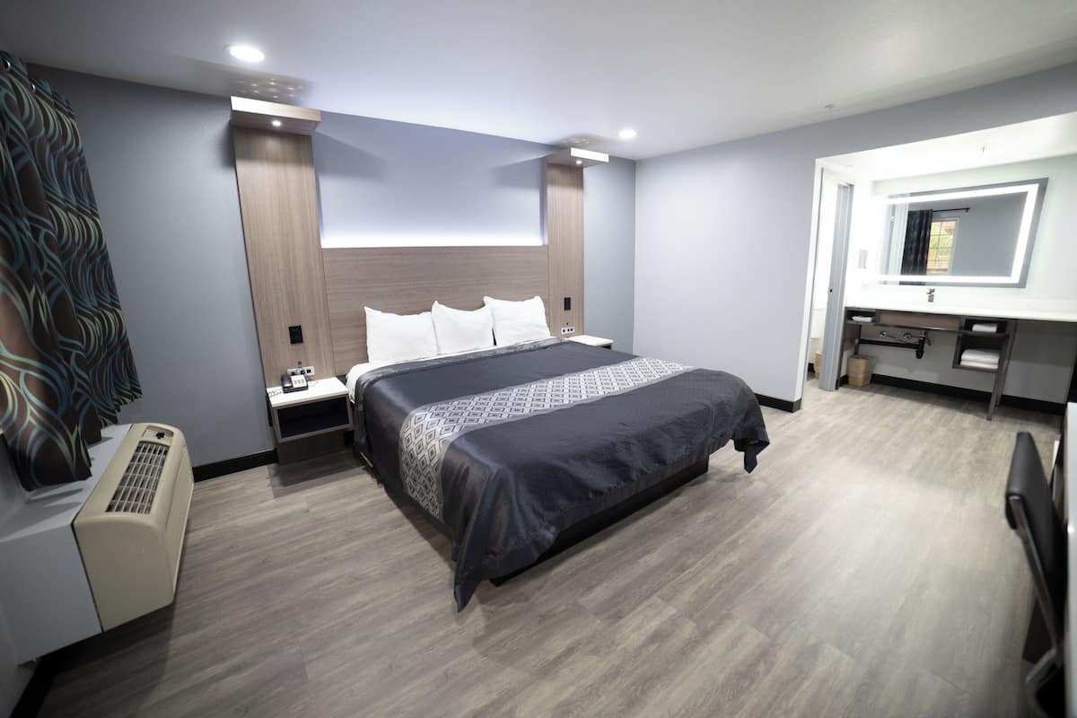 A hotel room with a bed, bedside tables, a desk, and a mirror.