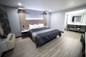A hotel room with a bed, bedside tables, a desk, and a mirror.