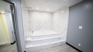 Une salle de bain moderne avec un mur en marbre, une baignoire et un plancher en bois.