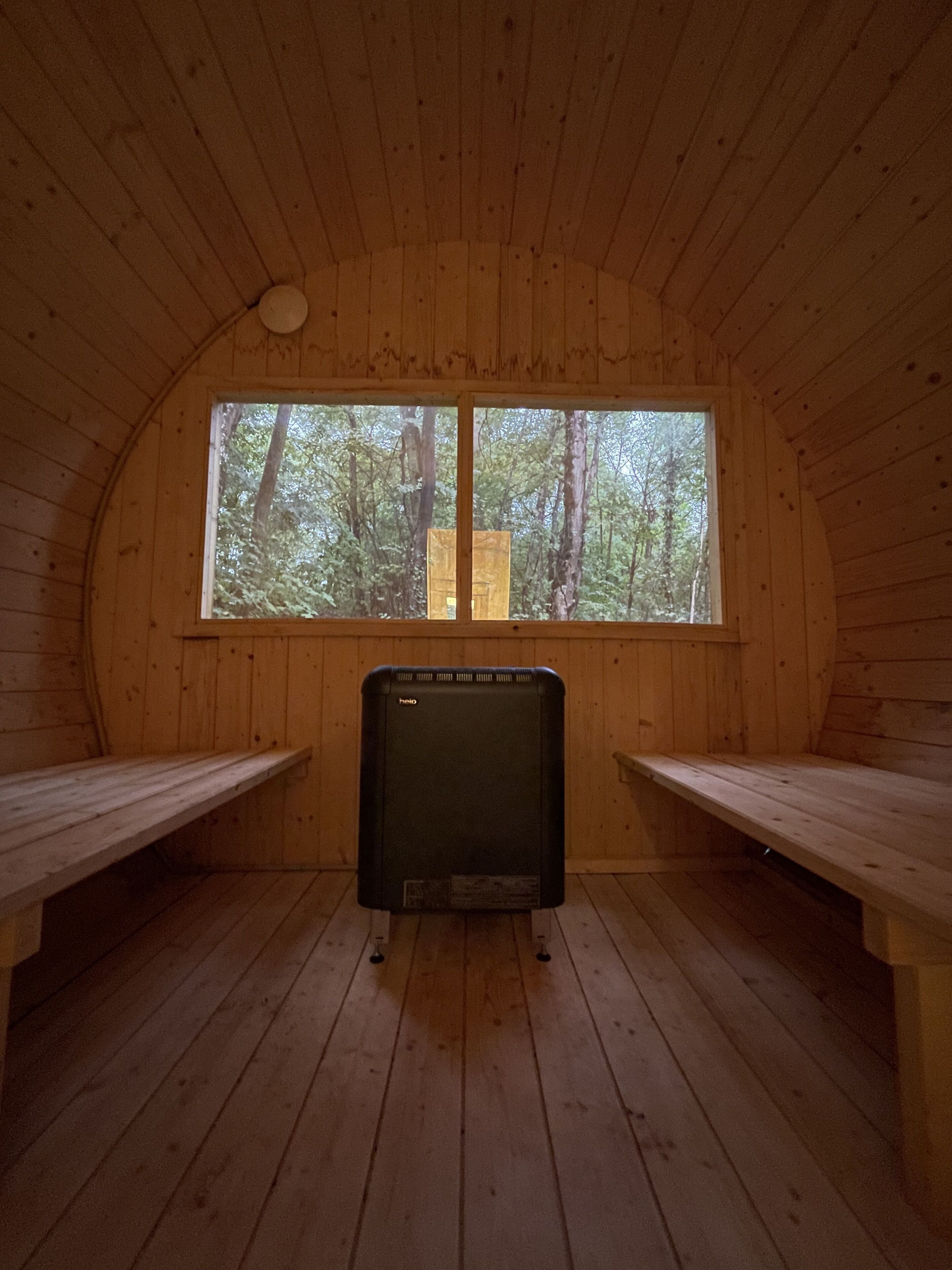 An interior with a wooden ceiling, a large window, and two benches.