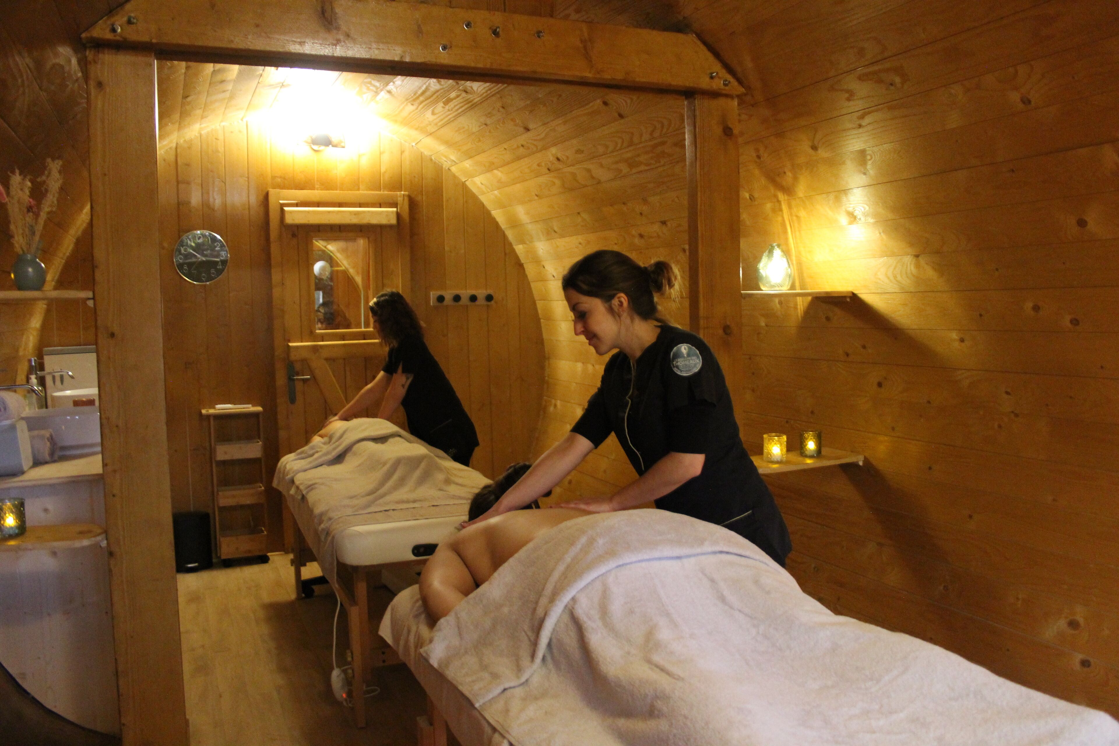 Une pièce en bois avec deux tables de massage, une horloge et un miroir.