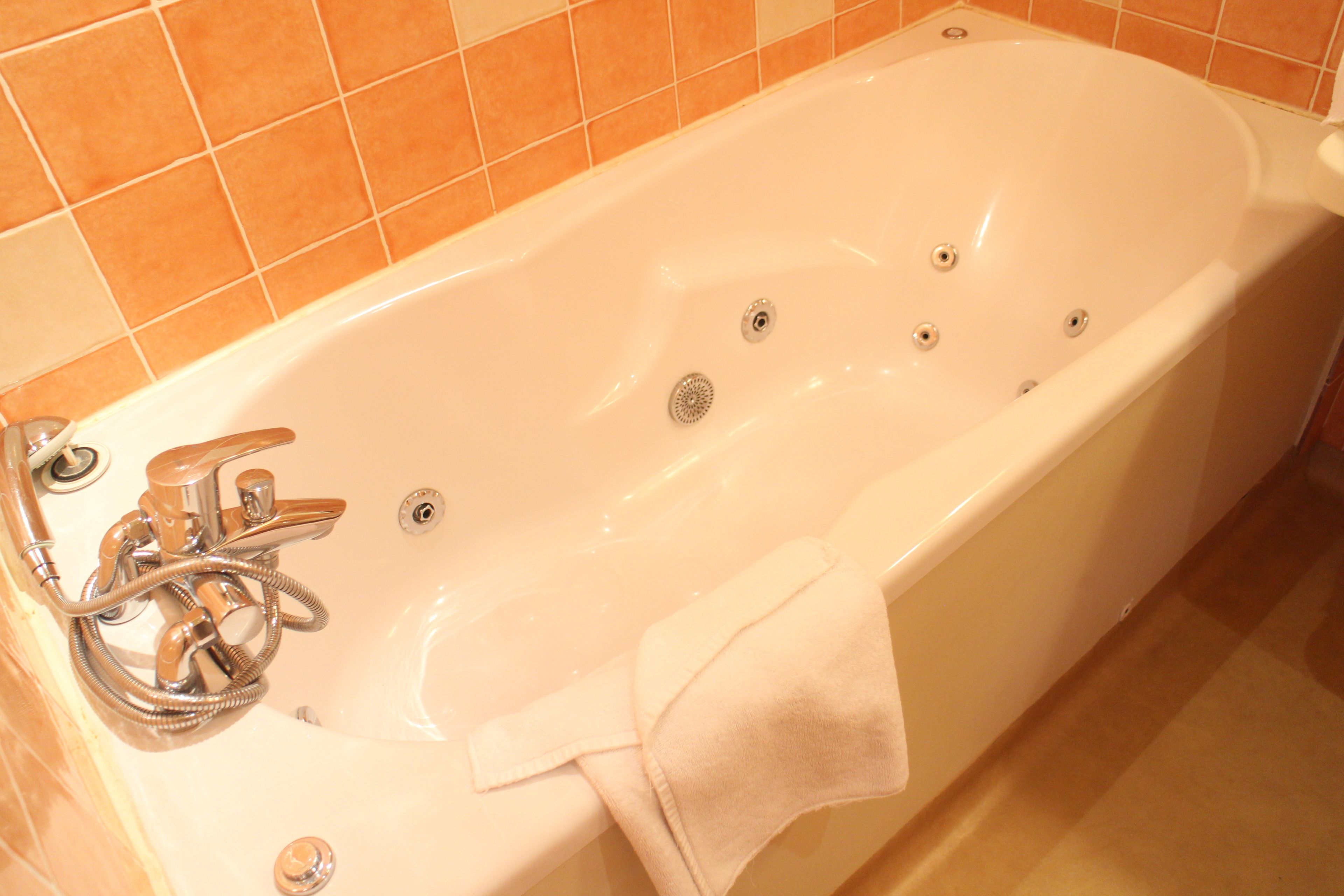 Une baignoire blanche avec un pommeau de douche et une serviette.