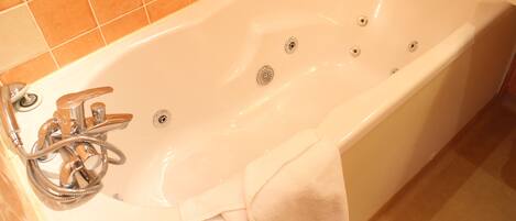 A white bathtub with a showerhead and a towel.