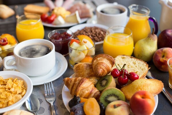 Un assortiment de produits pour le petit-déjeuner comprenant des croissants, des fruits et des boissons.