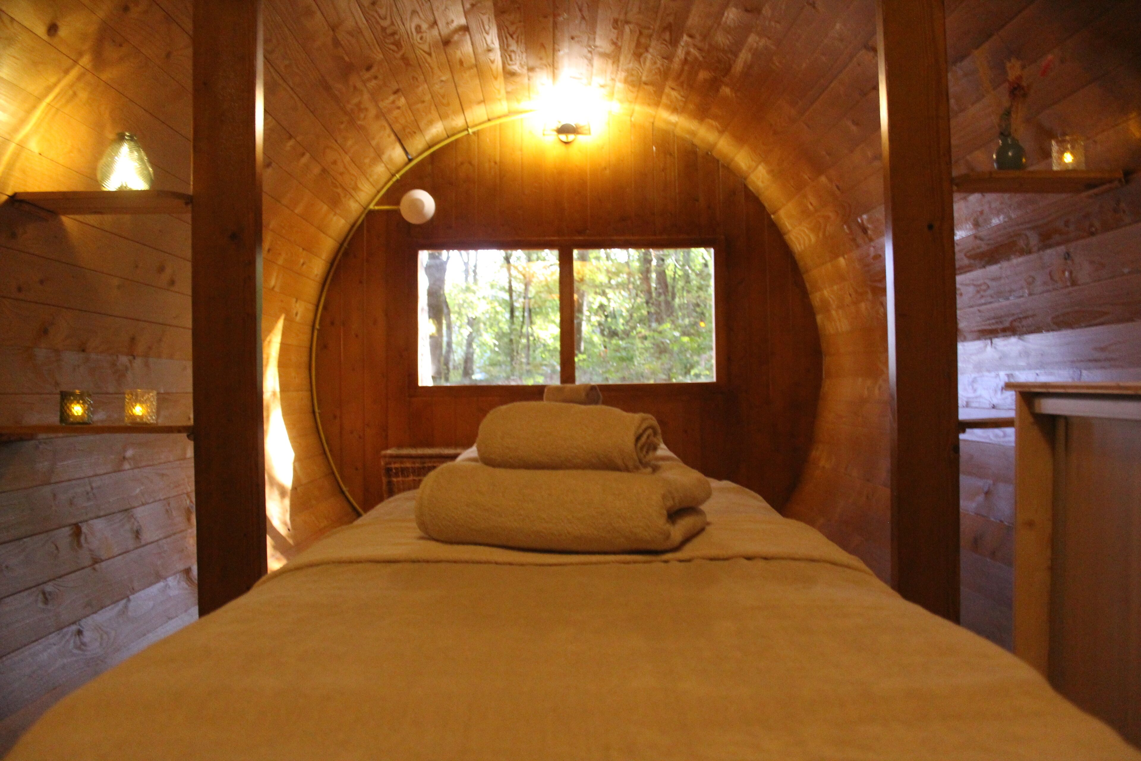 Een knus houten kamer met een bed, een raam en een plankje met een vaas.