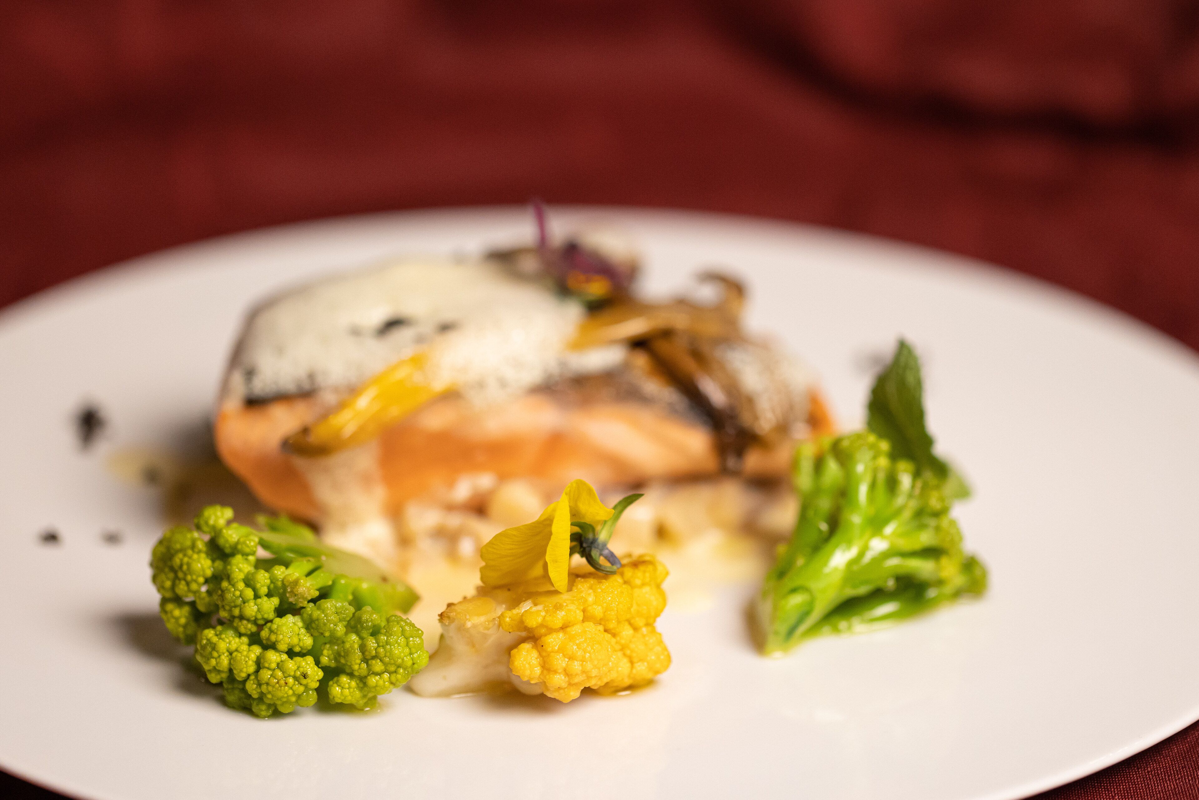 A plate with a piece of salmon, broccoli, and cauliflower.
