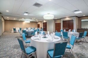 A conference room with round tables, blue chairs, and white tablecloths. - Hilton Garden Inn Augusta (Augusta)