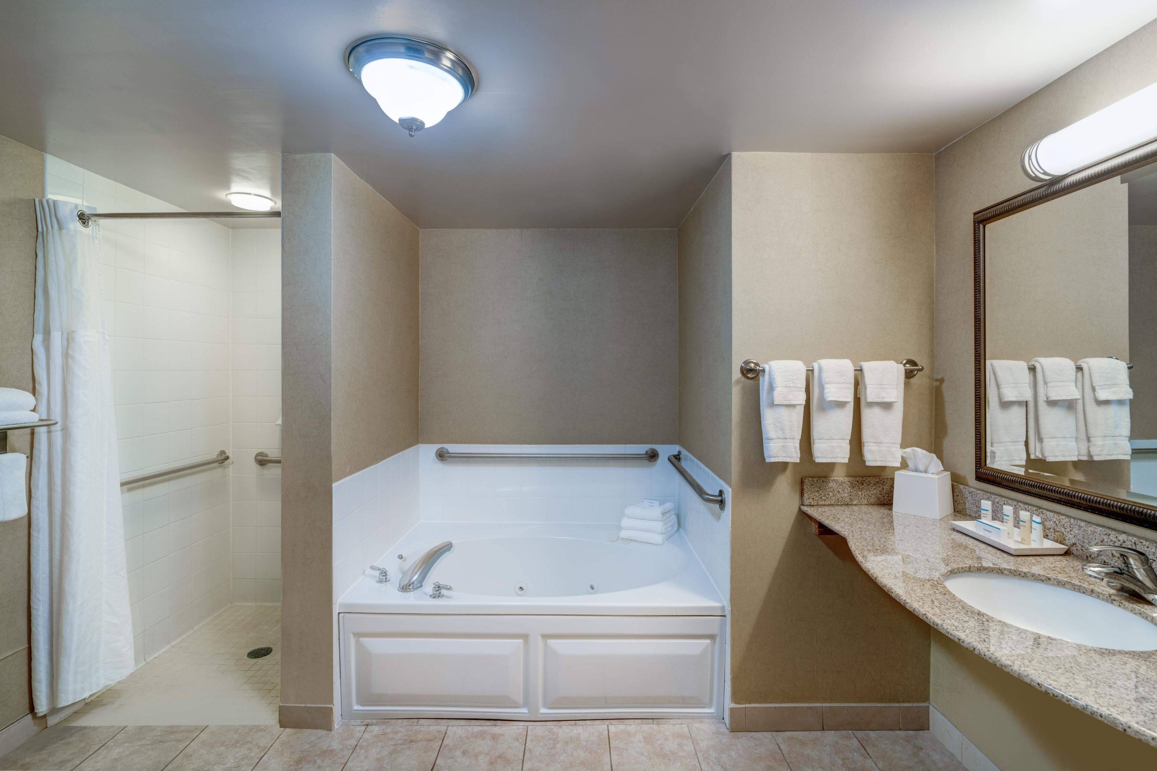 Une salle de bain moderne avec une douche à l’italienne, une baignoire sur pieds, un meuble-lavabo avec miroir et un porte-serviettes.