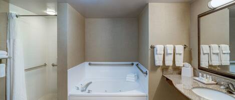 Un baño moderno con cabina de ducha a nivel, bañera independiente, tocador con espejo y un perchero para toallas.