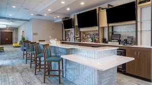 A modern kitchen with a bar area, seating, and a television. - Hilton Garden Inn Augusta (Augusta)