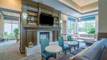 A modern lounge area with a fireplace, comfortable seating, and a flat-screen TV.