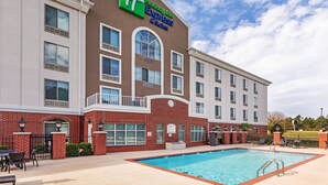 Un hotel con piscina, fachada de ladrillo y un letrero de Holiday Inn Express & Suites.