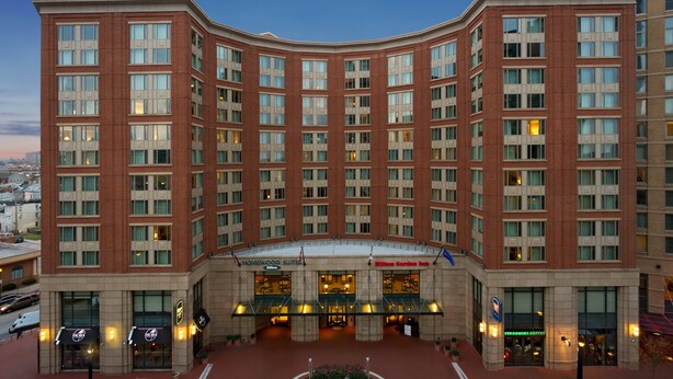 Ein großes, mehrstöckiges Hotel mit einer geschwungenen Fassade, das einen markanten Eingang mit Glastüren und ein Starbucks Coffee auf Erdgeschossniveau bietet.