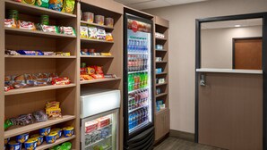 A snack and beverage vending area with various snack options and a Coca-Cola refrigerator.