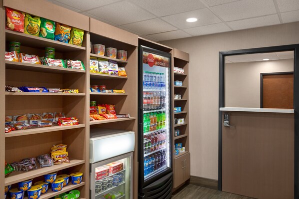 Espaço de distribuição automática com diversas opções de lanches e um refrigerador de Coca-Cola.