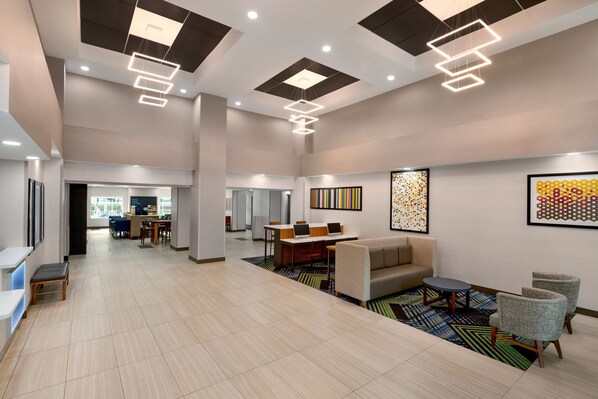 A spacious lobby with a reception desk, seating area, and artwork on the walls.