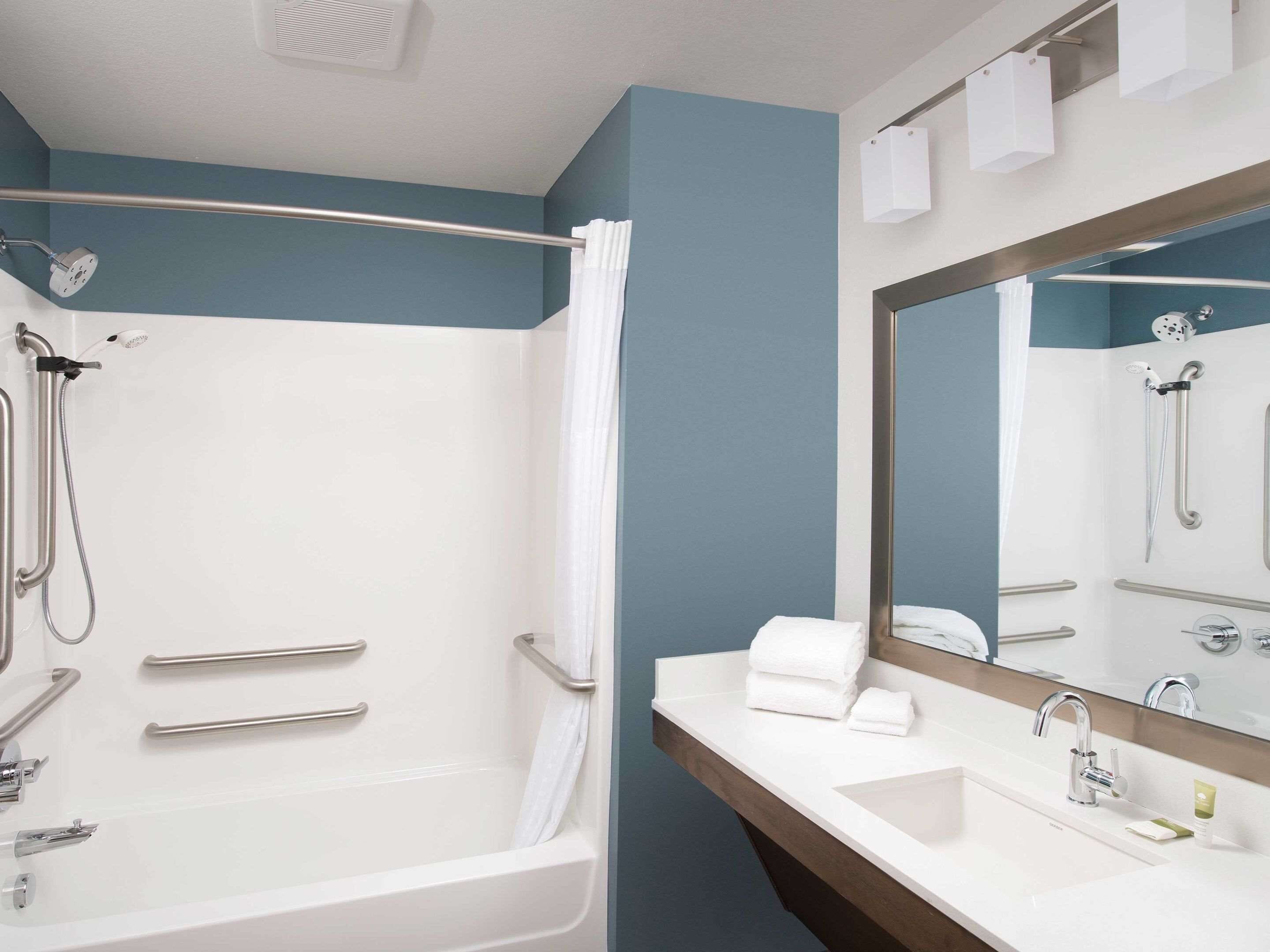 A modern bathroom with a bathtub, shower, and sink.