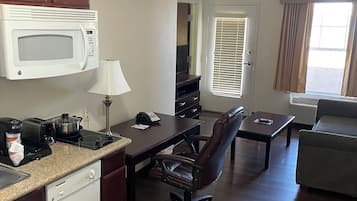 A compact kitchen with a microwave, toaster, and coffee maker. There's a dining area with a table and chairs, and a living room with a sofa.