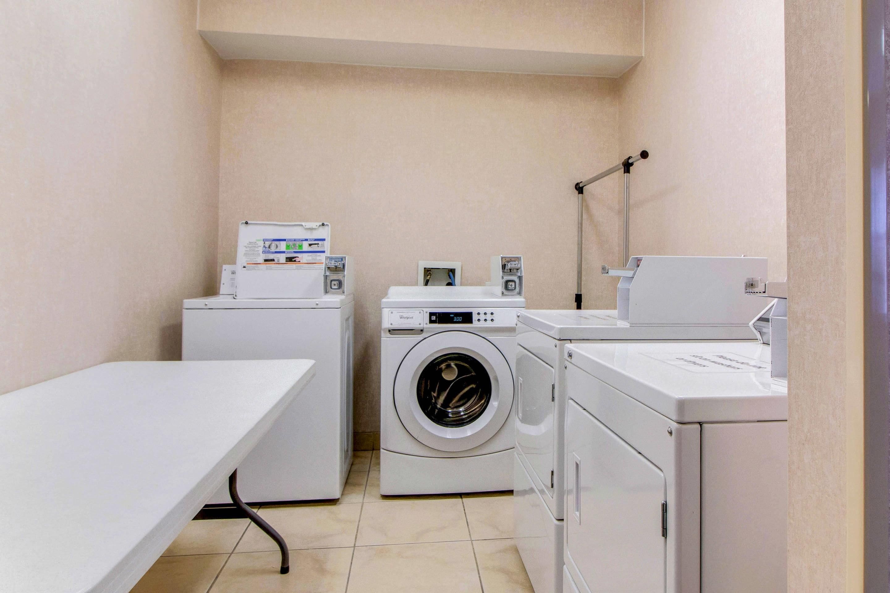 A laundry room with a washing machine, dryer, and a table.