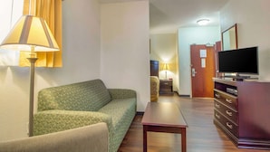 A hotel room with a sofa, a small table, a TV on a dresser, and a lamp. - MainStay Suites Texas Medical Center/Reliant Park (Houston)