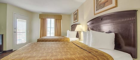 Une chambre d’hôtel avec un grand lit, une table de chevet avec une lampe, une fenêtre avec des rideaux et un tableau au mur.