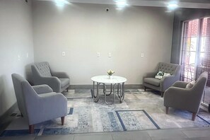 Una habitación con una mesa redonda, cuatro sillones, un tapete estampado y una ventana con vistas.