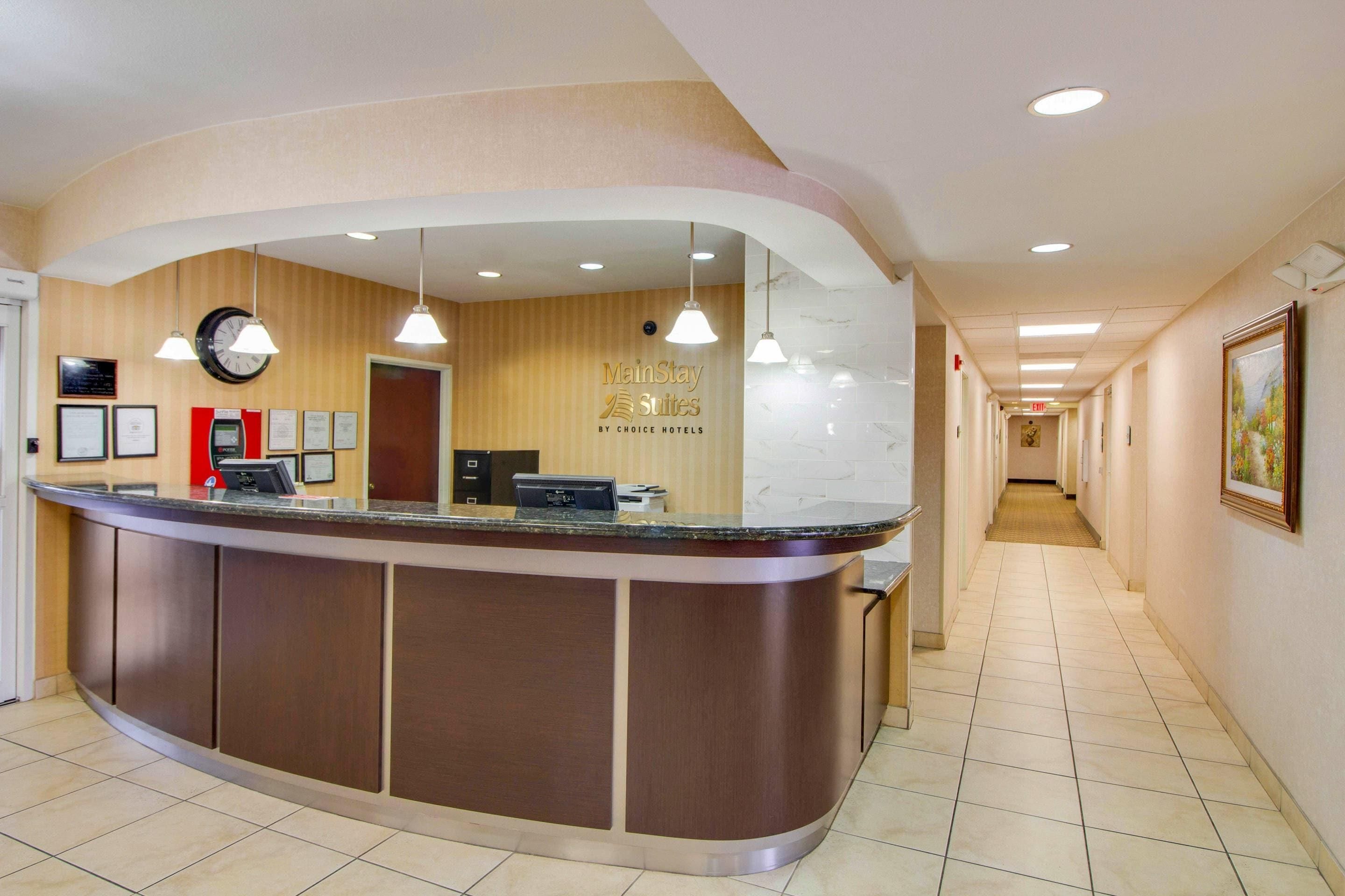 A hotel reception desk with a curved design, a clock, and framed certificates on the wall.