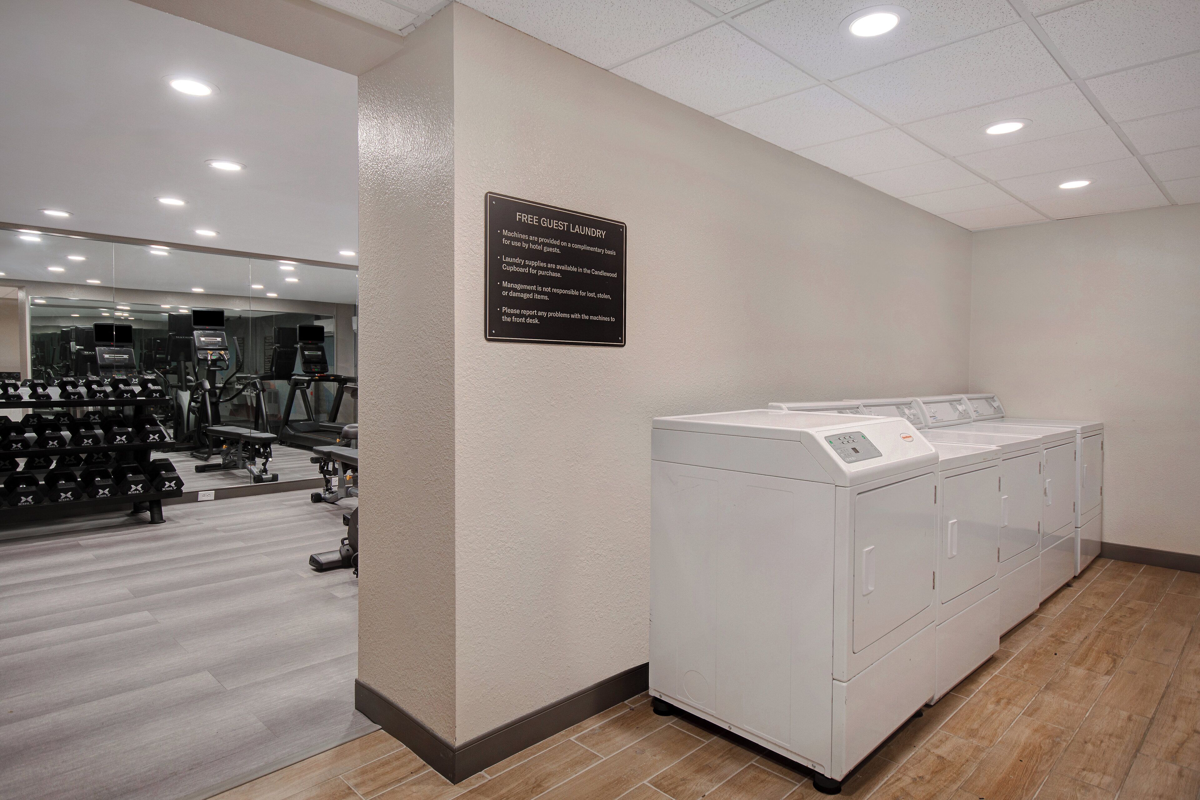 A hotel room with a large mirror, a white laundry machine, and a rack of dumbbells.