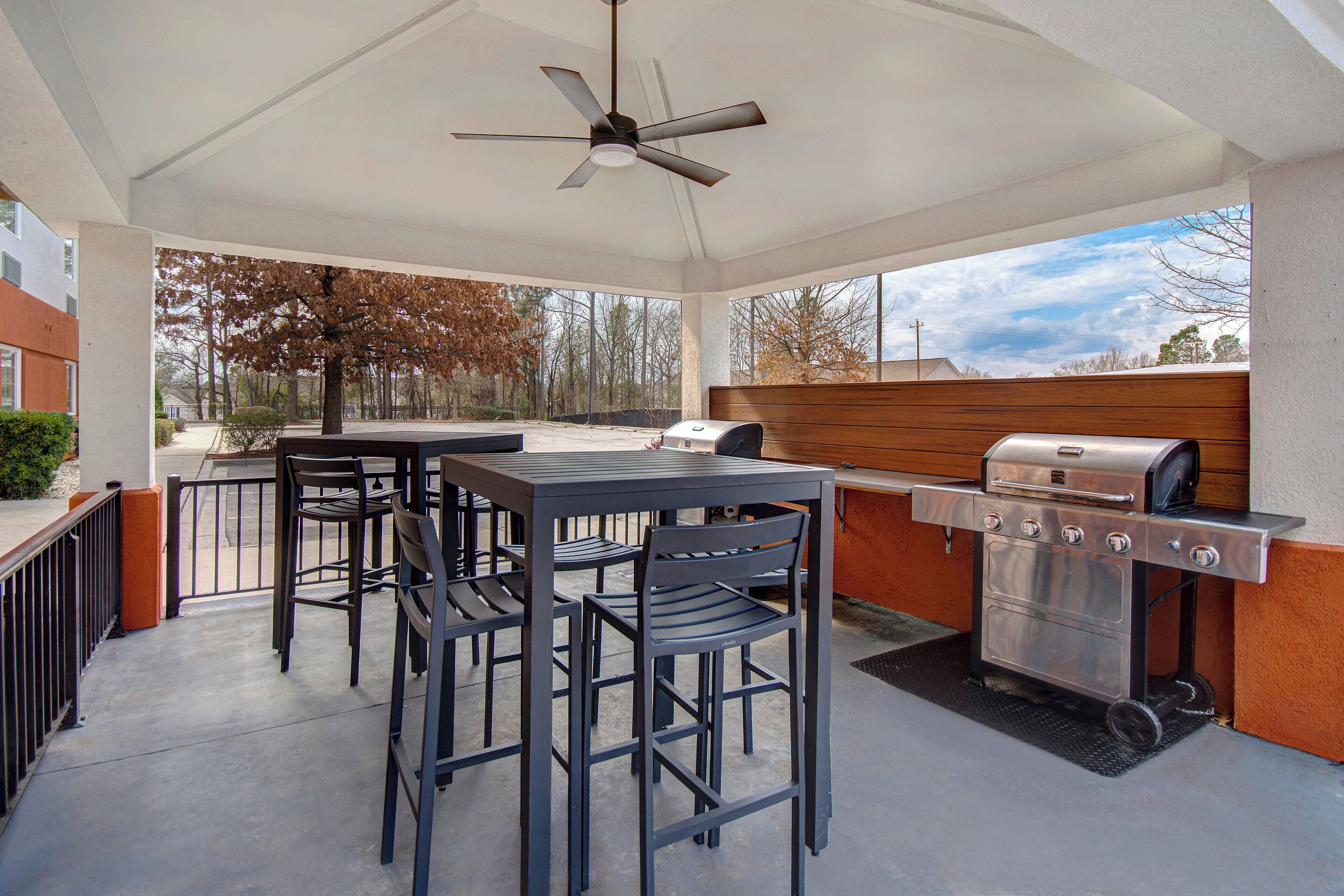 An outdoor patio with a table and chairs, a grill, and a ceiling fan.