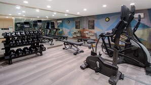 A gym with treadmills, dumbbells, benches, and a mirrored wall.