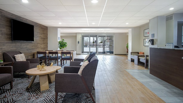 A spacious lobby with a reception desk, comfortable seating area, and a large flat-screen TV mounted on the wall.