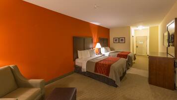 A hotel room with two beds, a desk, a chair, and a bathroom visible in the background.