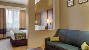 A hotel room with a bed, a sofa, a mirror, and two framed pictures on the wall. - Comfort Inn & Suites Amarillo East (Amarillo)