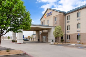 Welcome to Comfort Inn & Suites, featuring a covered entrance and parking area, surrounded by a tree.