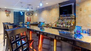 A bar area with a long counter, multiple seating options, and a variety of bottles and glasses. - Comfort Inn & Suites Amarillo East (Amarillo)