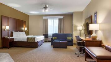 A hotel room with a bed, a sofa, a desk, a chair, and a TV.