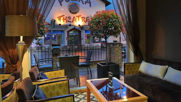 Um hall acolhedor com móveis de vime, uma mesa de centro de vidro e vista para o Polka Theatre.