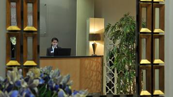 A reception desk with a computer, a lamp, and a potted plant.