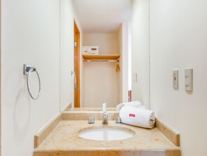 Un baño con un lavamanos de mármol, una toalla, un espejo y un estante con una toalla.