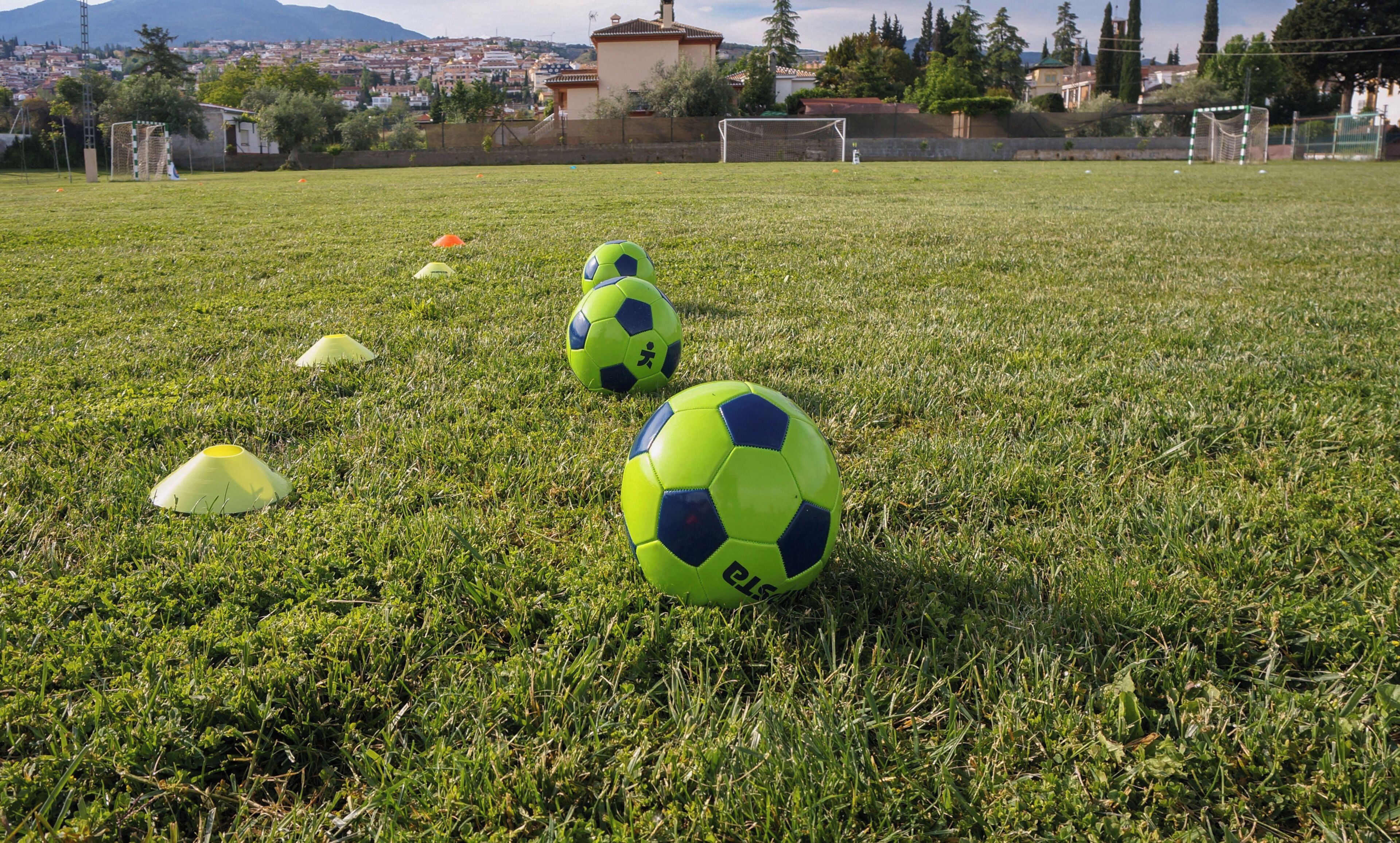 Um campo de futebol com várias bolas e cones de treinamento.