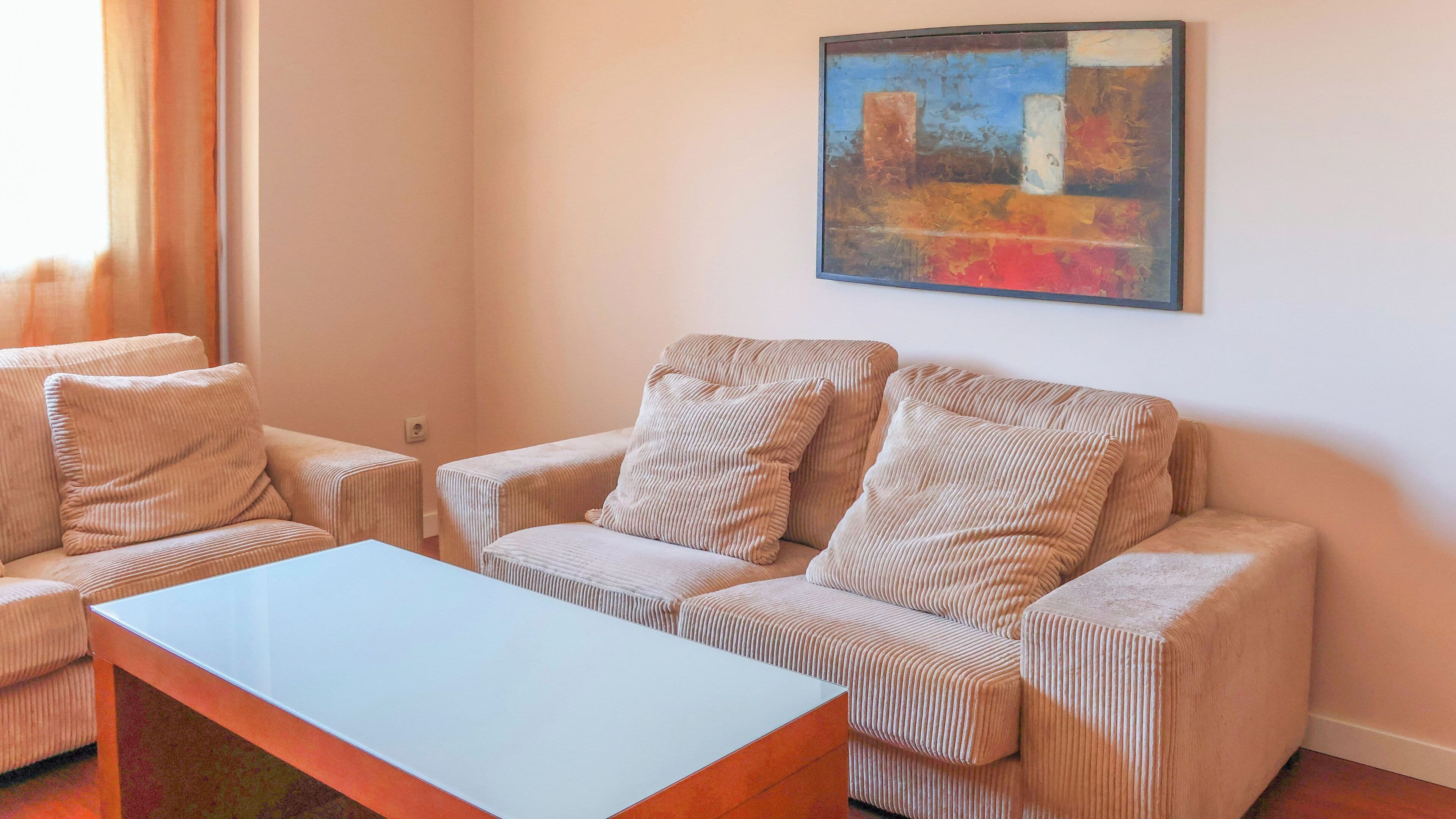 A living room with a sofa, two armchairs, a coffee table, and a painting on the wall.
