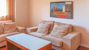Una sala de estar con un sofá, dos sillones, una mesa de centro y un cuadro en la pared.