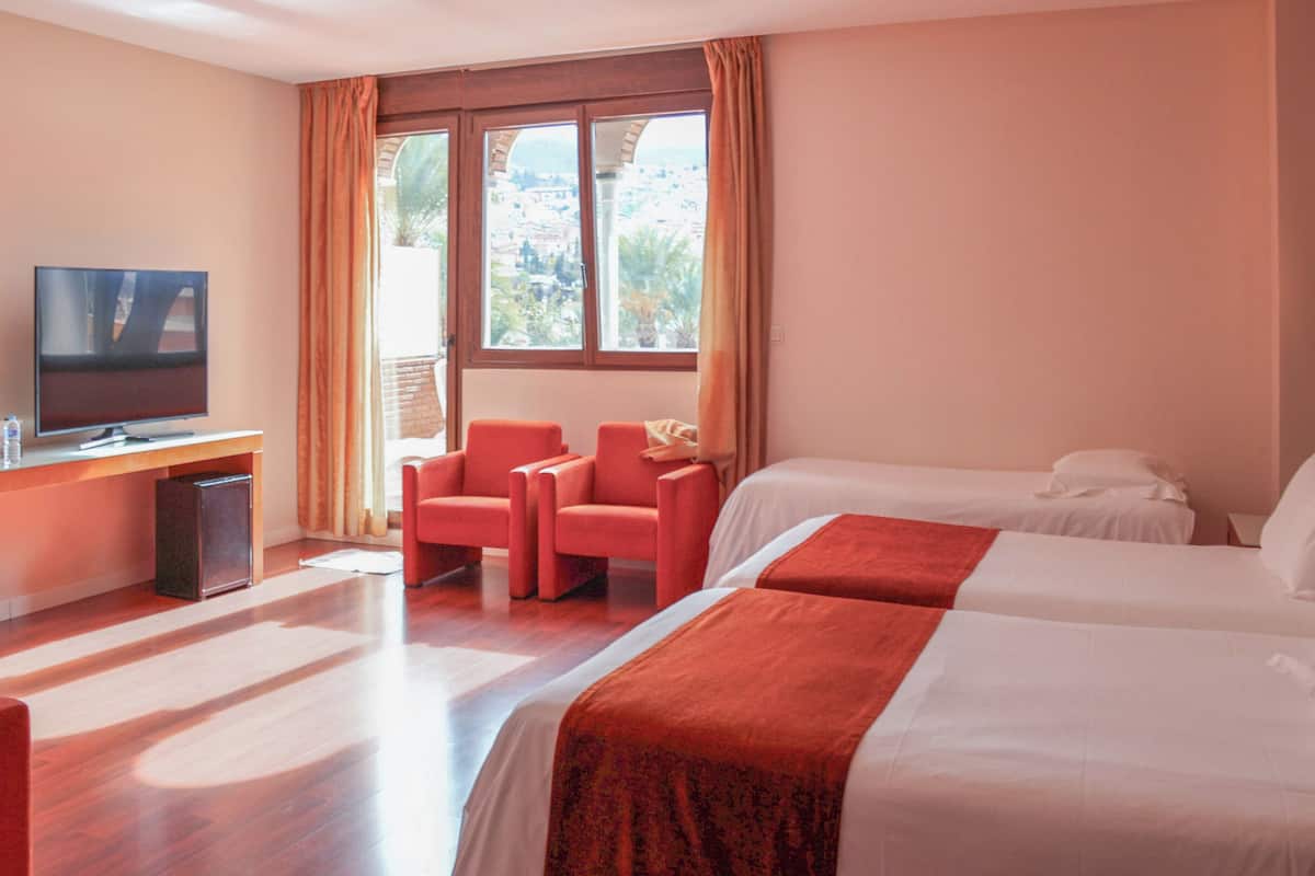 A hotel room with a TV, two beds, a desk, and a chair.