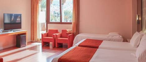 A hotel room with a TV, two beds, a desk, and a chair.