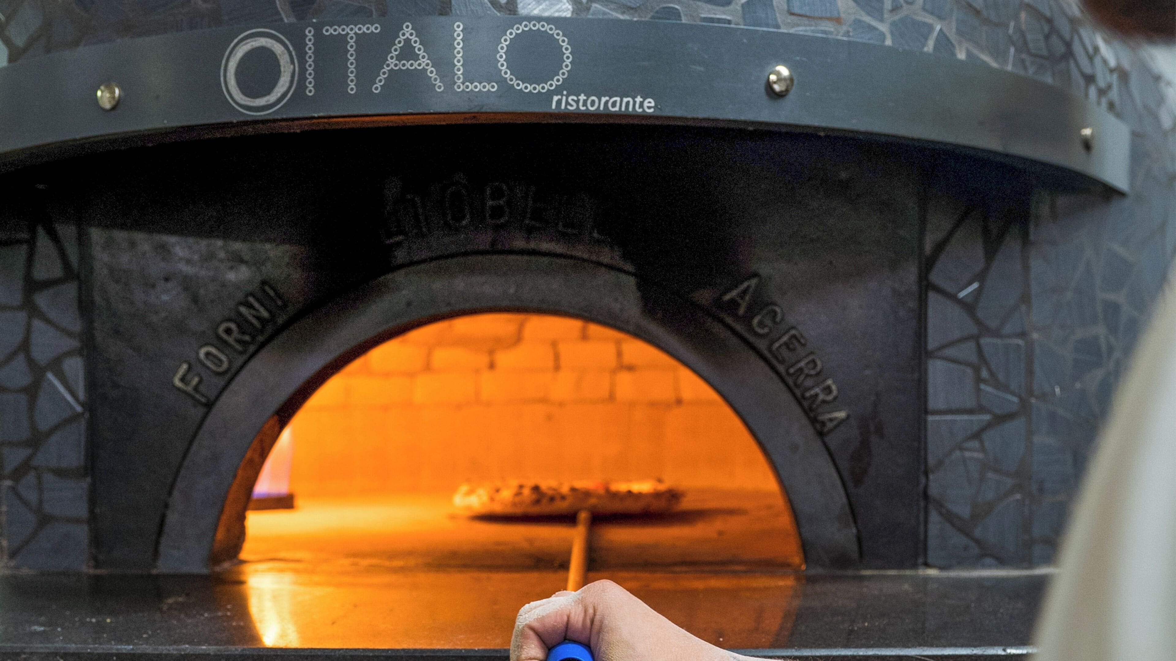 Um forno de pizza com a marcação 'OITALO' e 'ACERBA' na porta, indicando uma pizzaria.