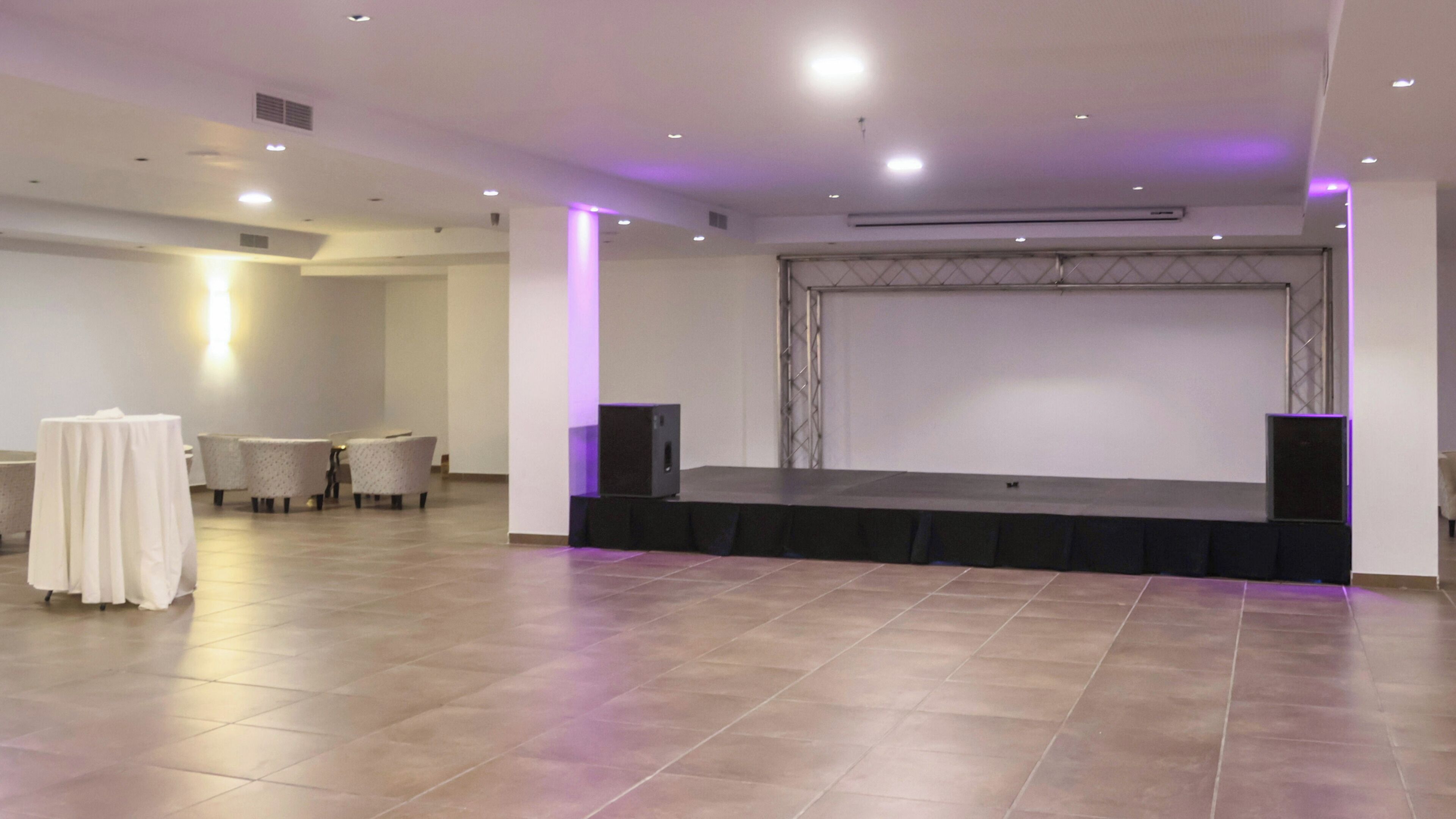 Un salón de conferencias con un escenario, asientos y equipo de audio.