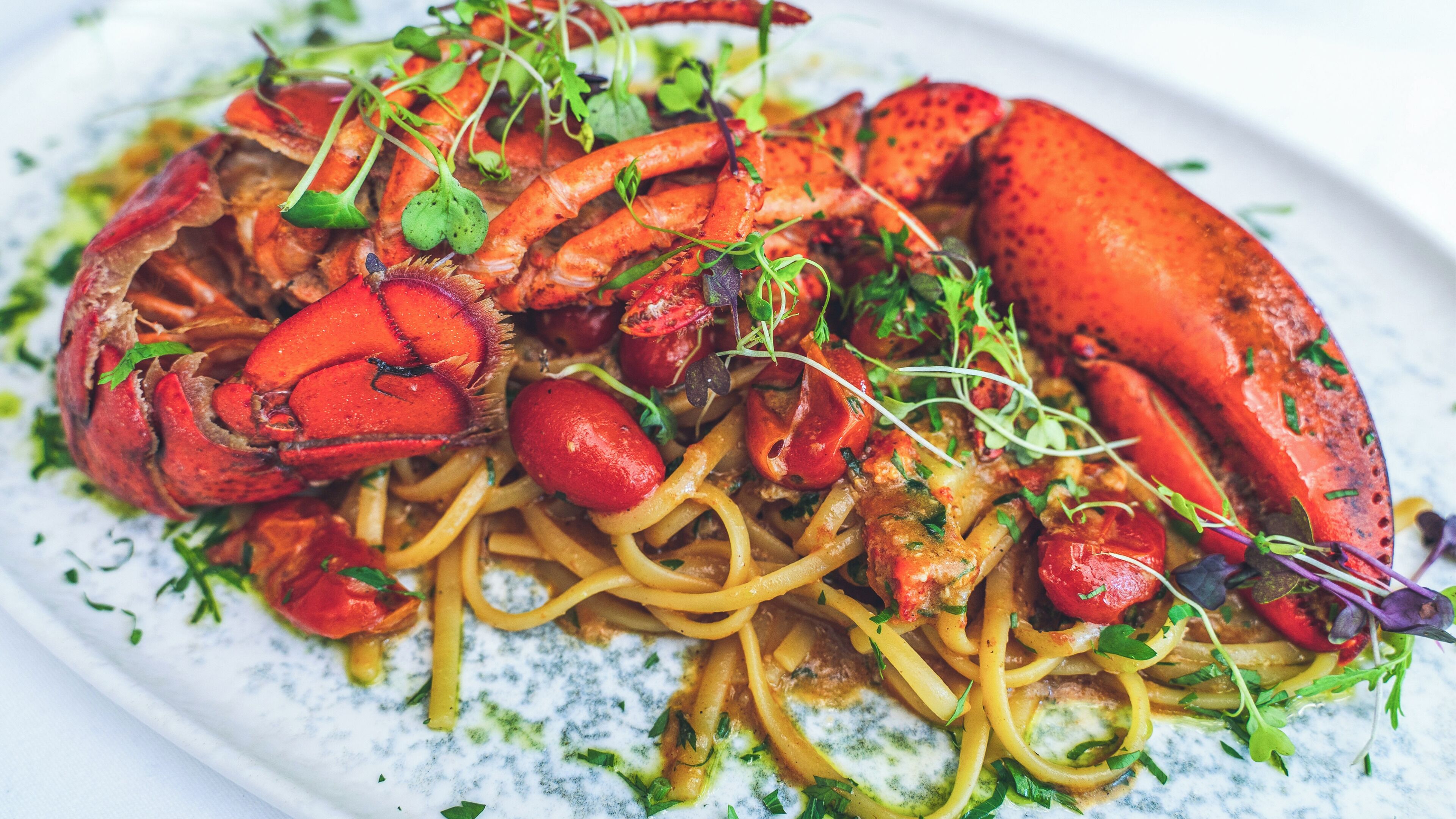 Un plat de spaghetti amb una cua de langosta gran i guarnició de verdura.