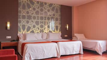Habitación de hotel con dos camas, una silla roja, suelo de madera y decoración mural con estampado.
